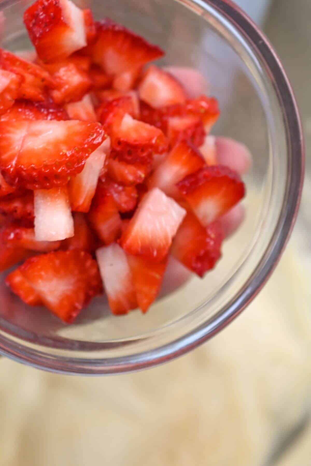 Pouring diced strawberries into pound cake batter.