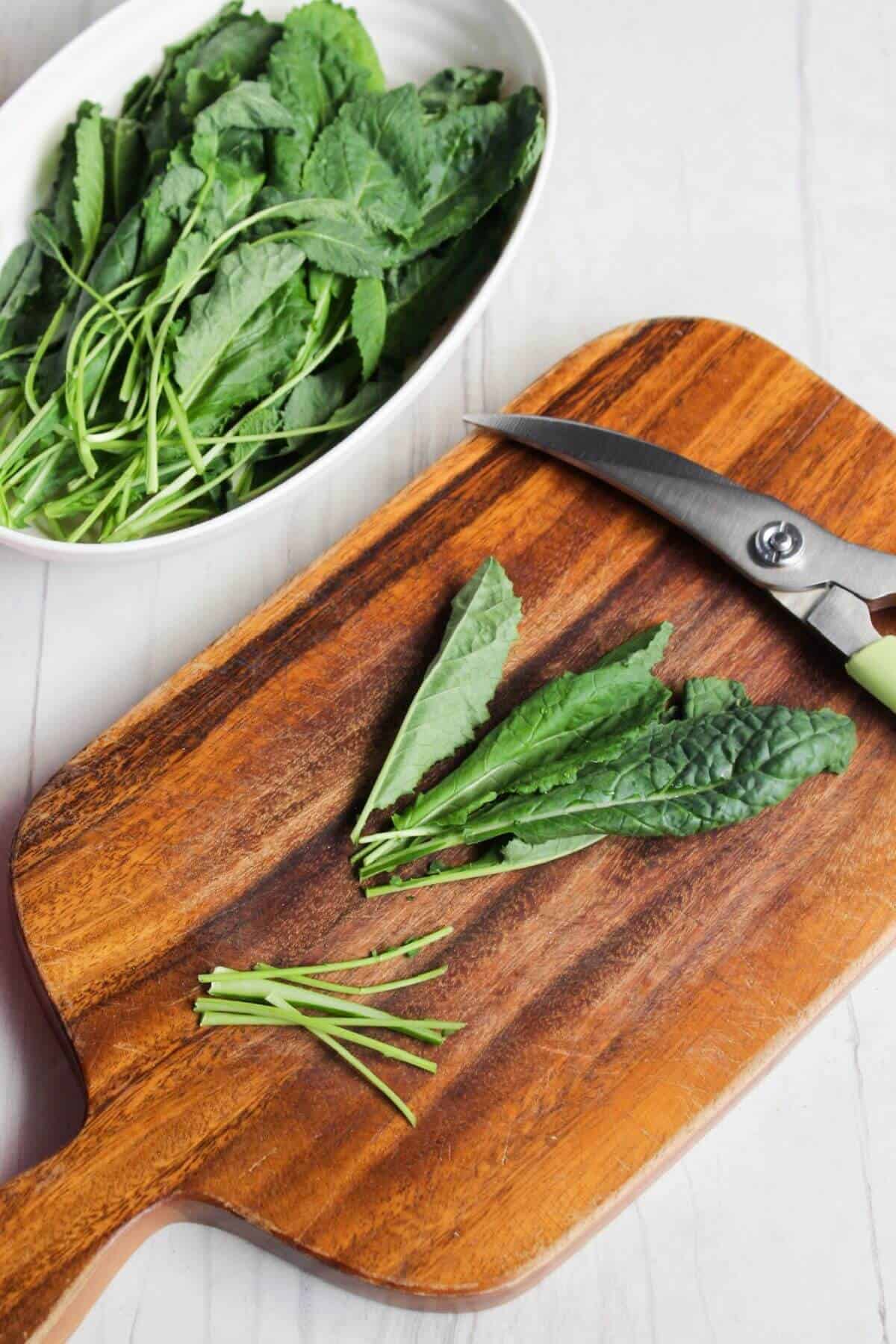 Kale leaves on a cutting board next to a pair of scissors.