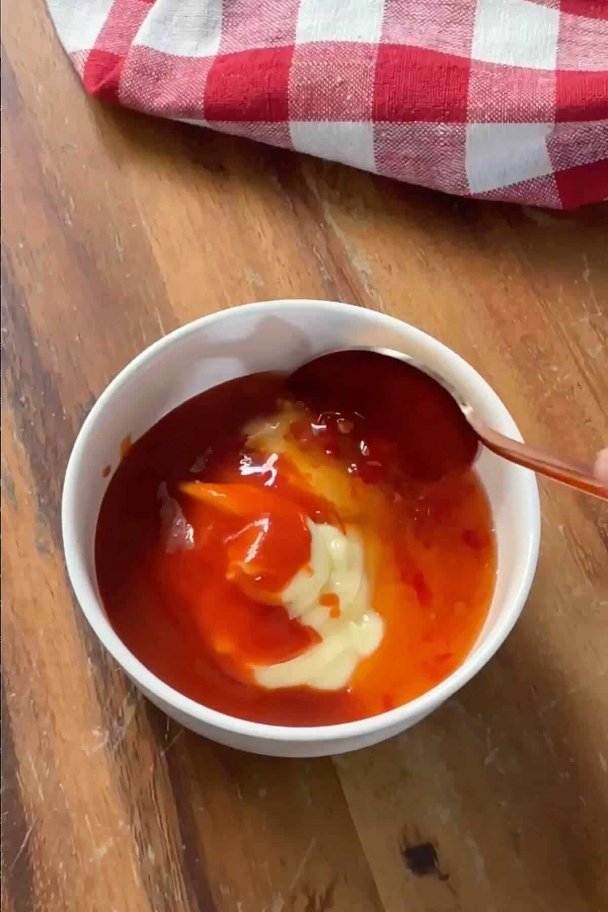A bowl of bang bang sauce with a spoon in it.