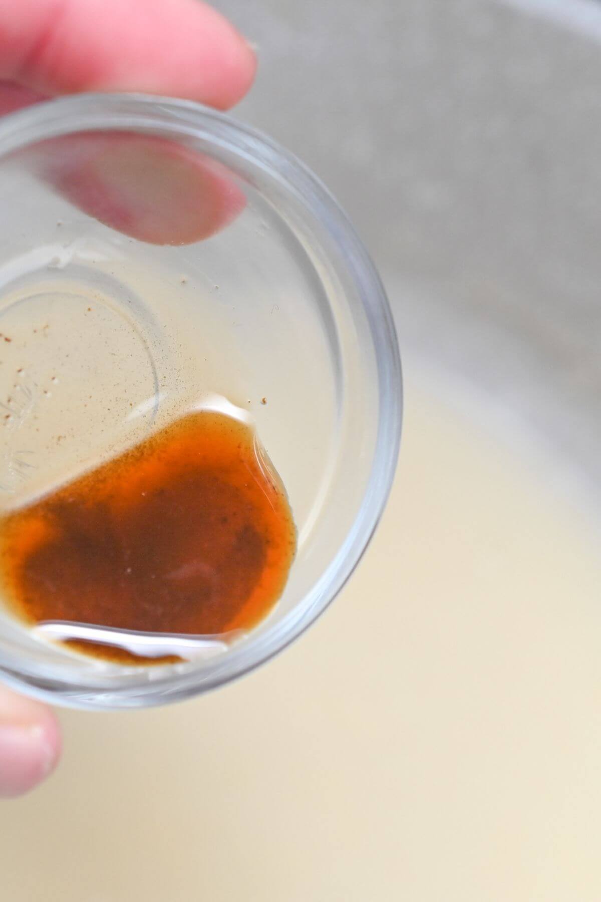 A person holding a glass bowl with Worcestershire sauce in it.