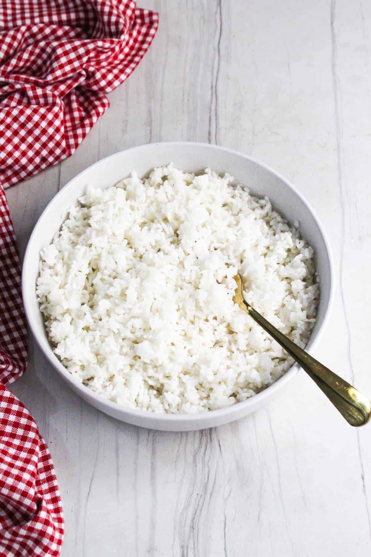 White rice in a bowl on a wooden table.
