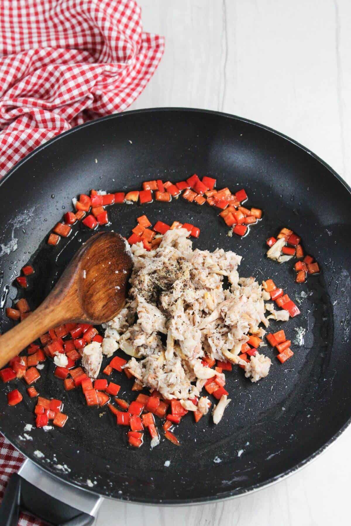 A frying pan with chopped vegetables and crab meat.