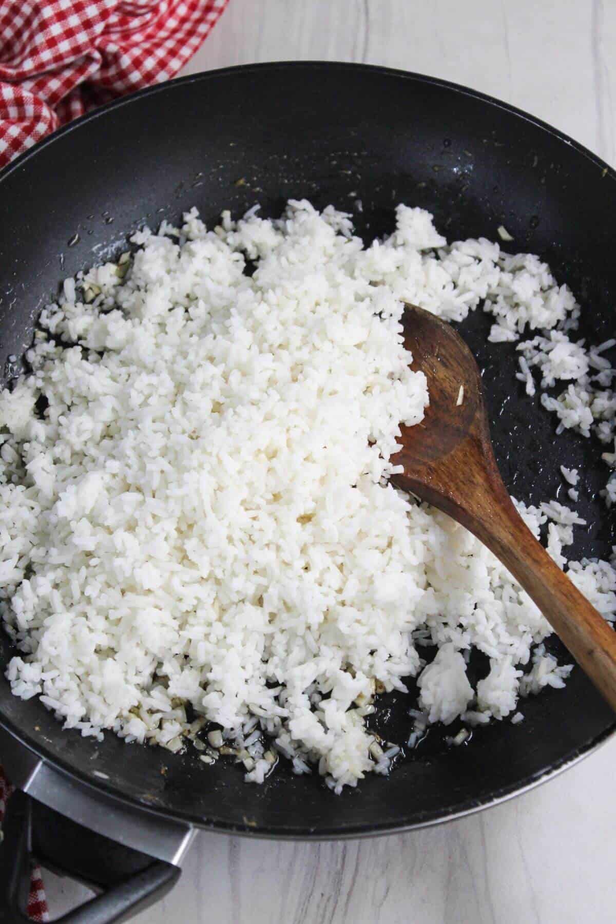 Rice in a frying pan with a wooden spoon.