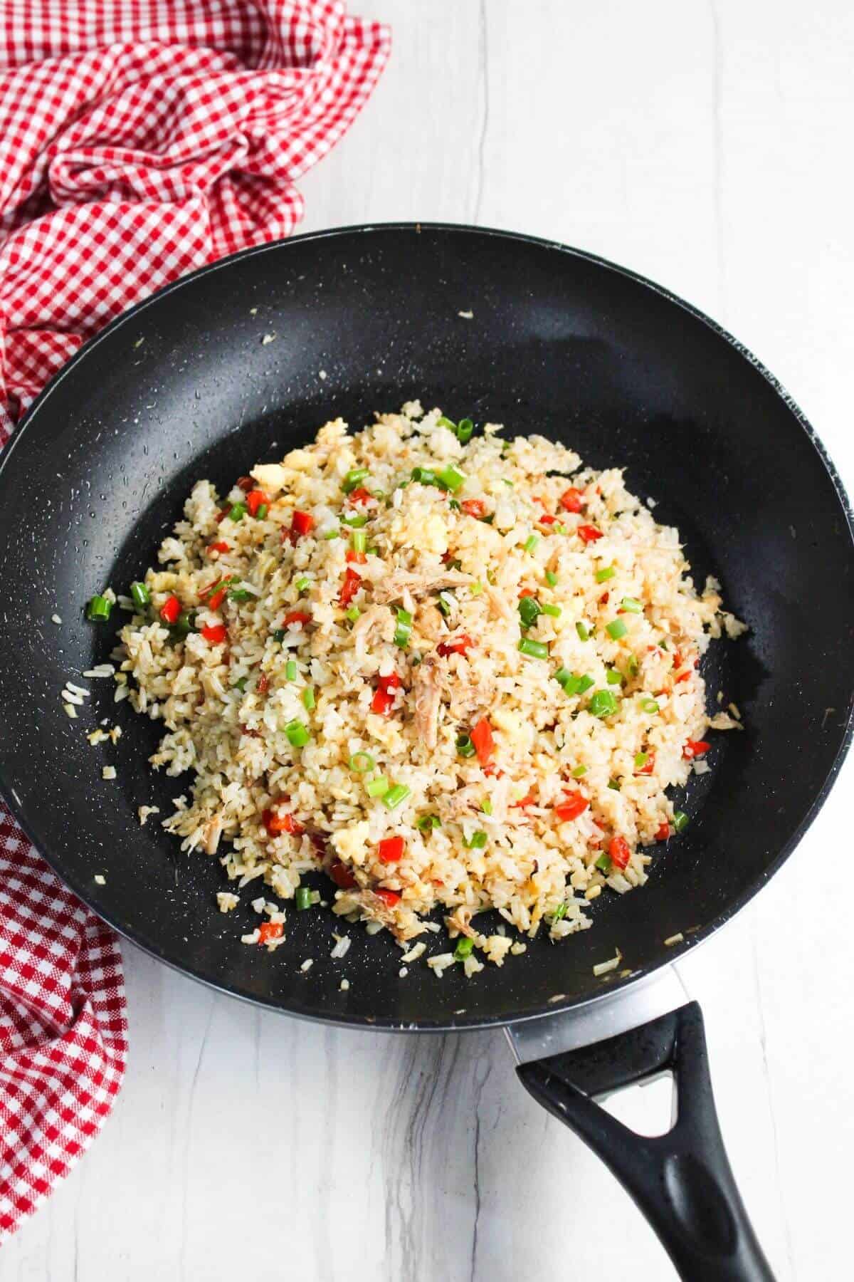 Fried rice in a frying pan on a wooden table.
