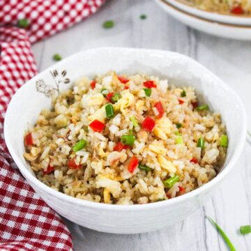 Two bowls of fried rice on a red and white checkered tablecloth.