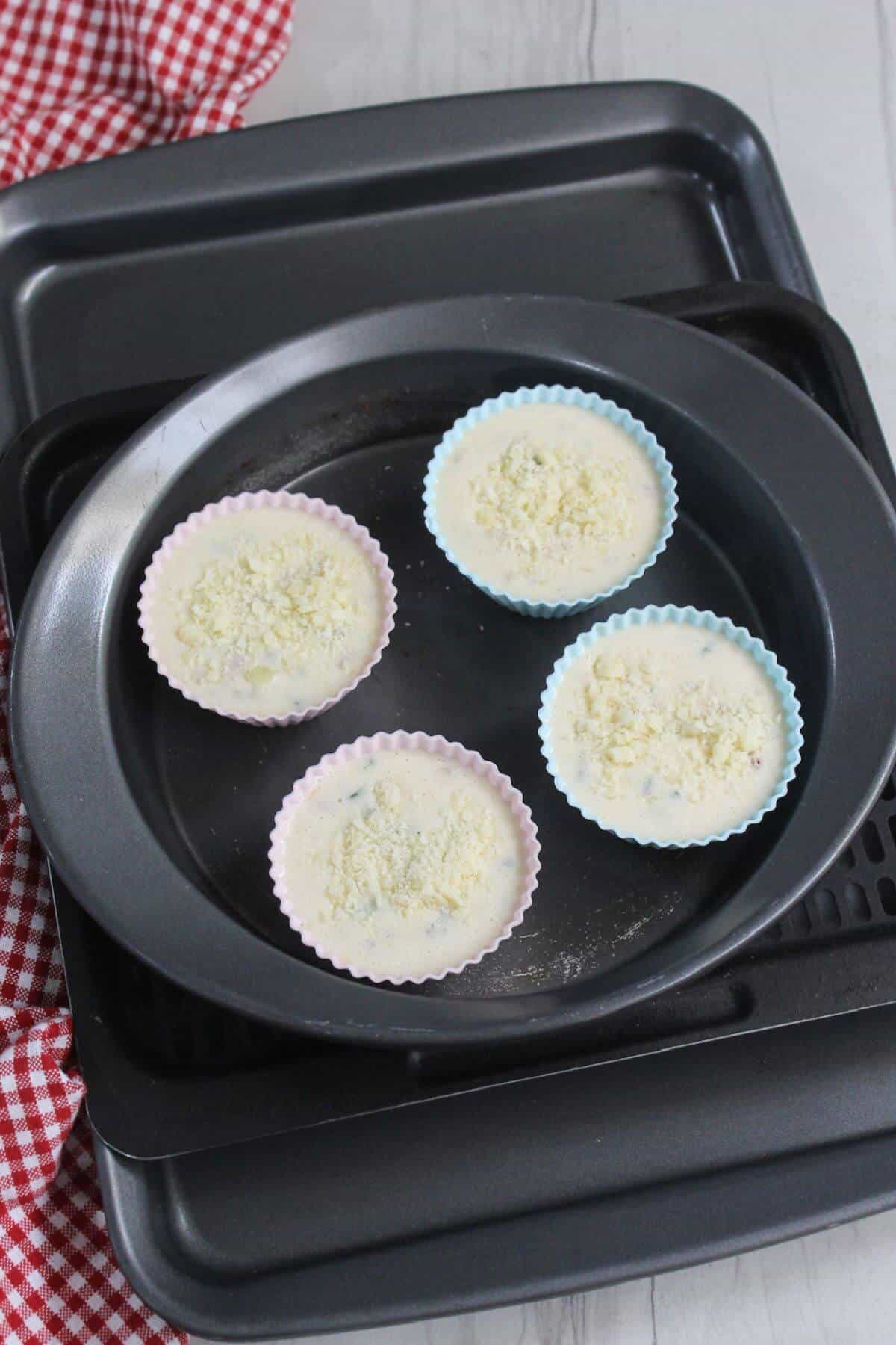 A group of uncooked egg white frittata muffins in a pan on air fryer tray.