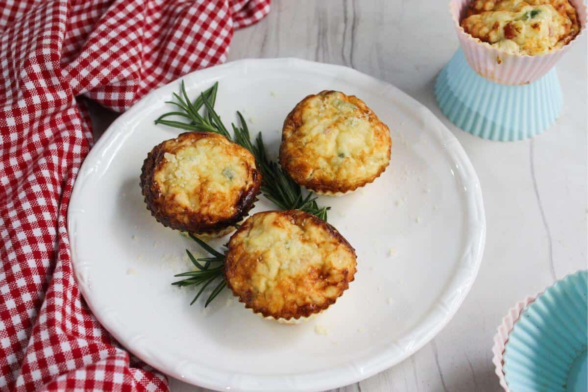 Three egg white frittata muffins on a plate with sprigs of rosemary.