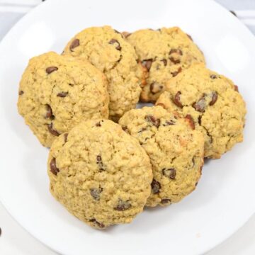 A plate of oatmeal chocolate chip cookies on a white surface.