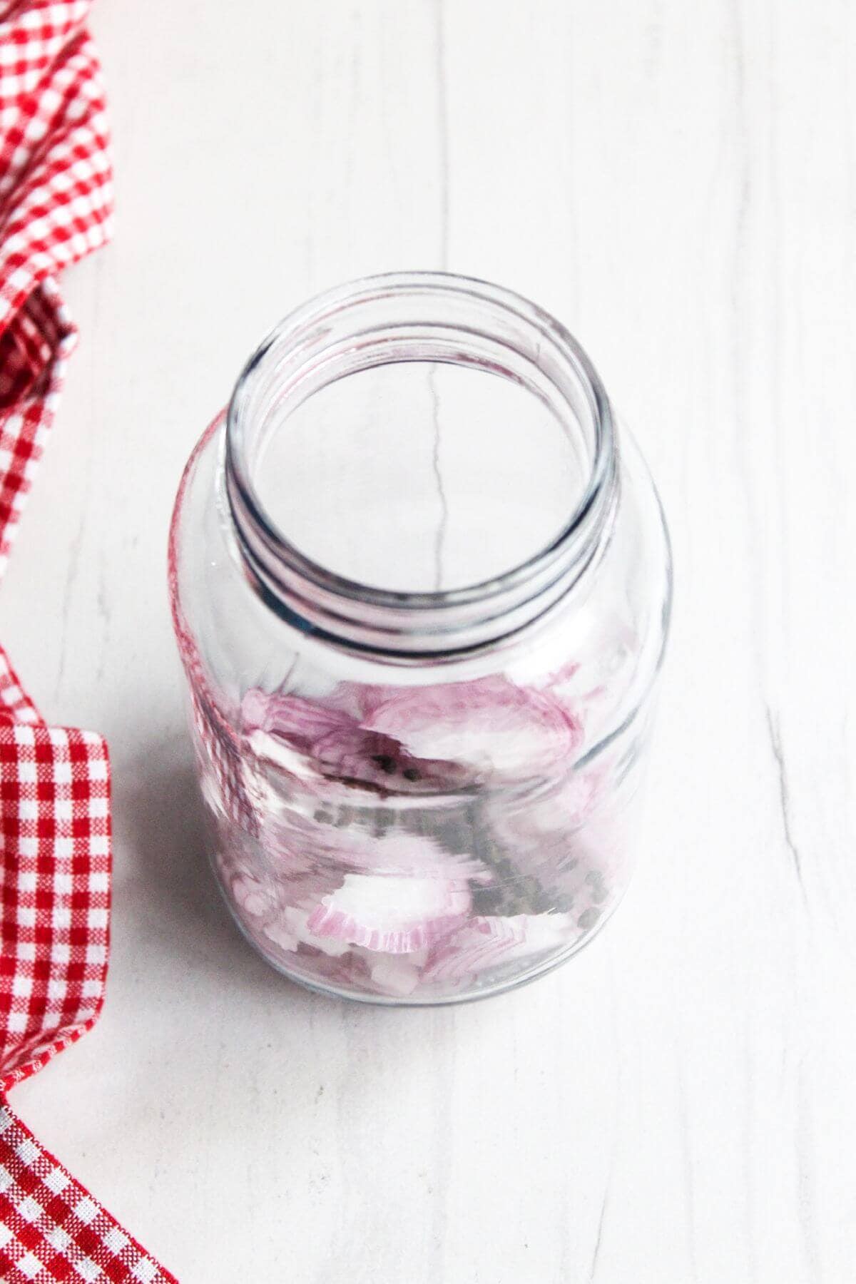 A glass jar with sliced red onions in it.