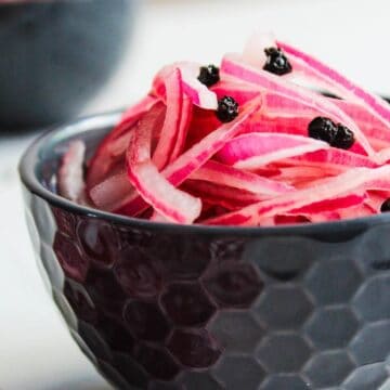 A bowl of pickled red onions on a table.