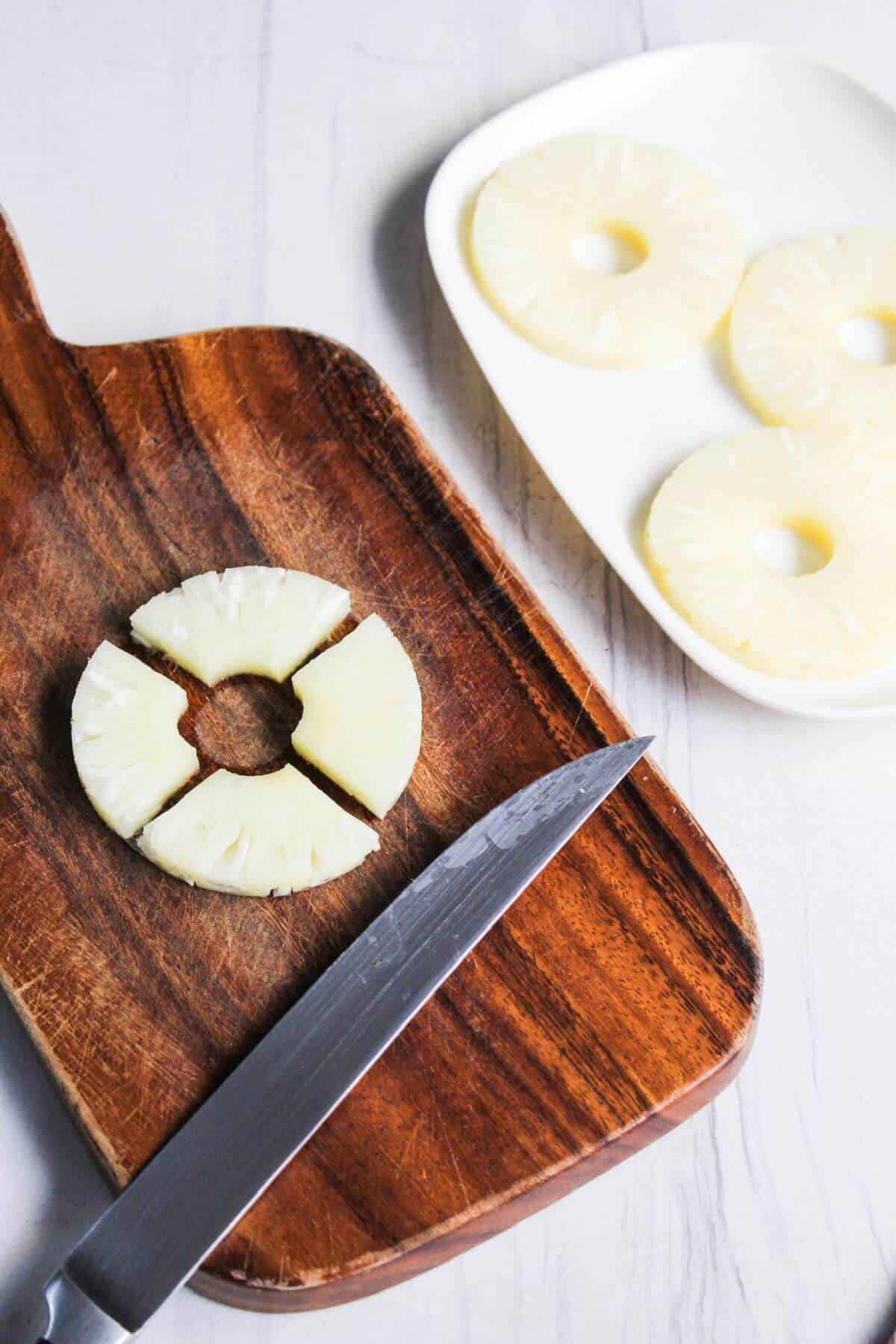 Pineapple slices on a cutting board with a knife.