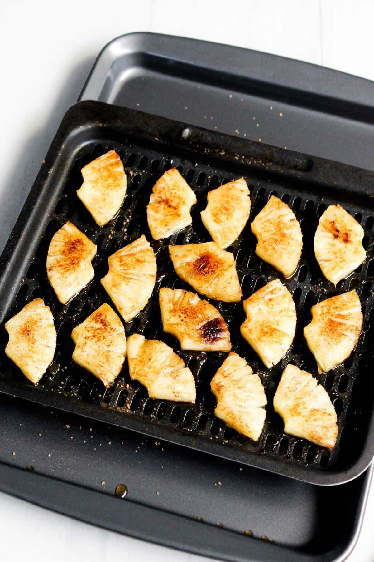 Grilled pineapple slices on an air fryer tray.