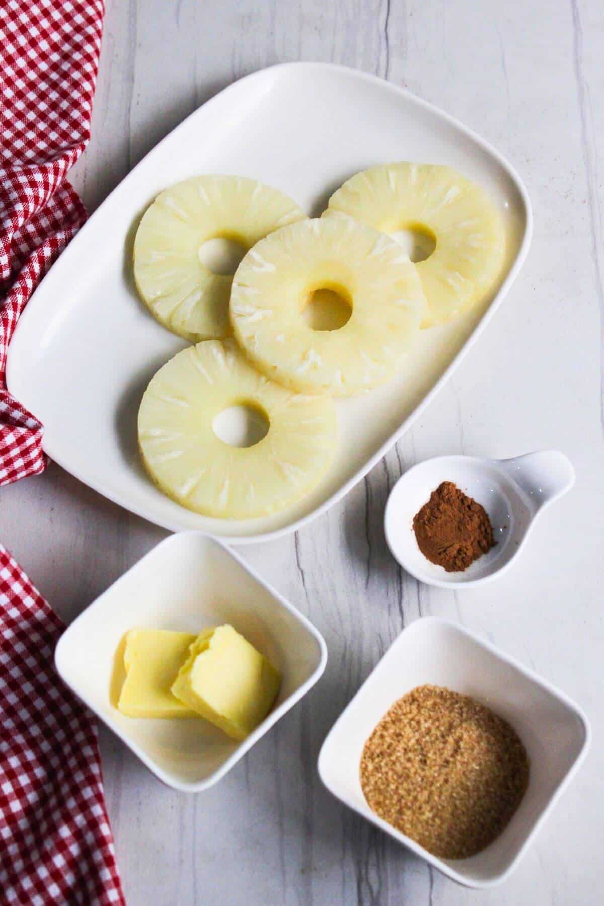 A plate with pineapple slices, cinnamon, brown sugar and butter.