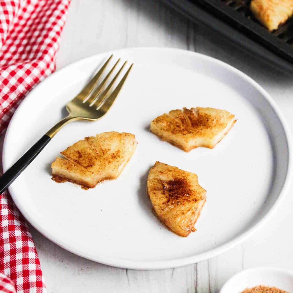 Air fryer pineapples on a plate with a fork.