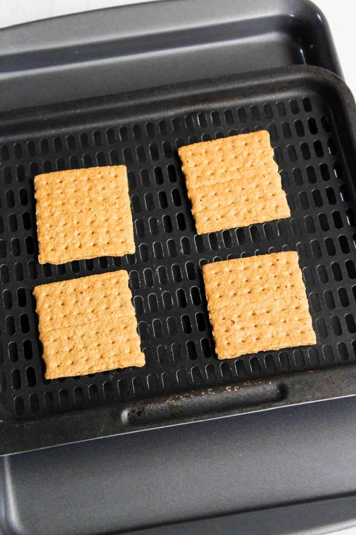 Four squares of graham crackers on an air fryer tray.