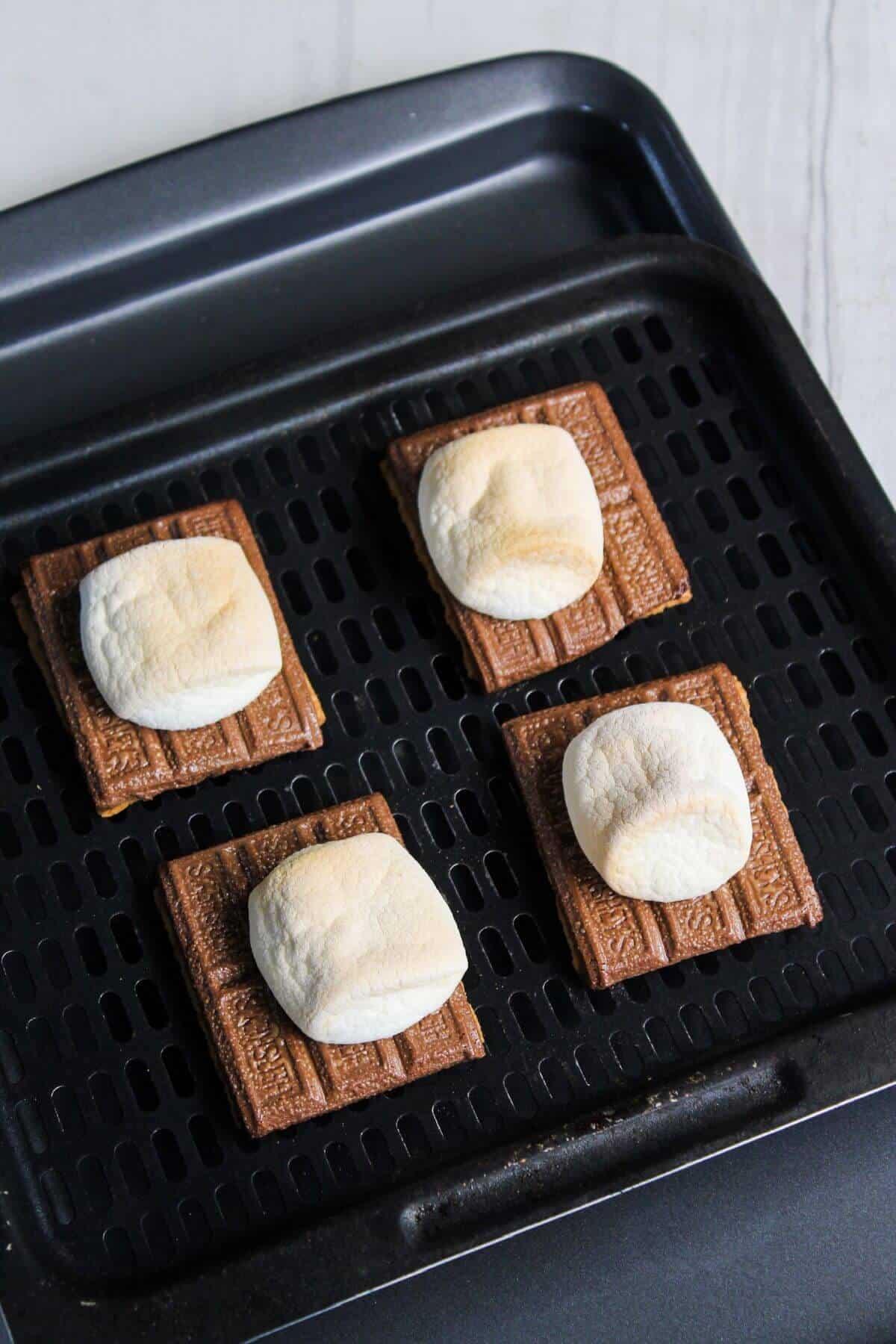 Four s'mores are sitting on an air fryer tray