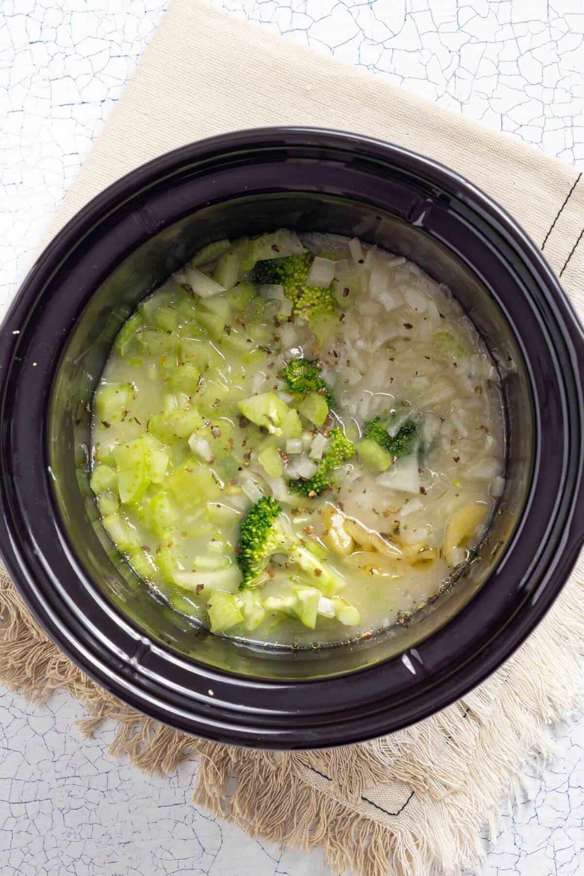 A crock pot of soup with broccoli and broccoli in it.