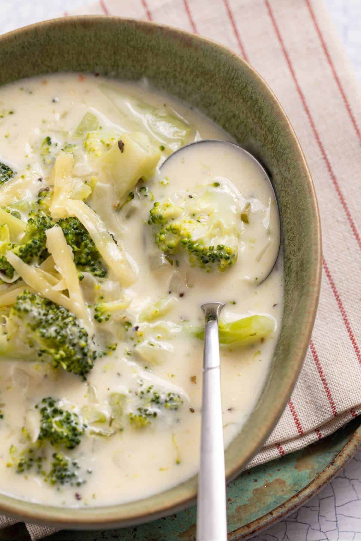 A bowl of broccoli and cheese soup with a spoon.