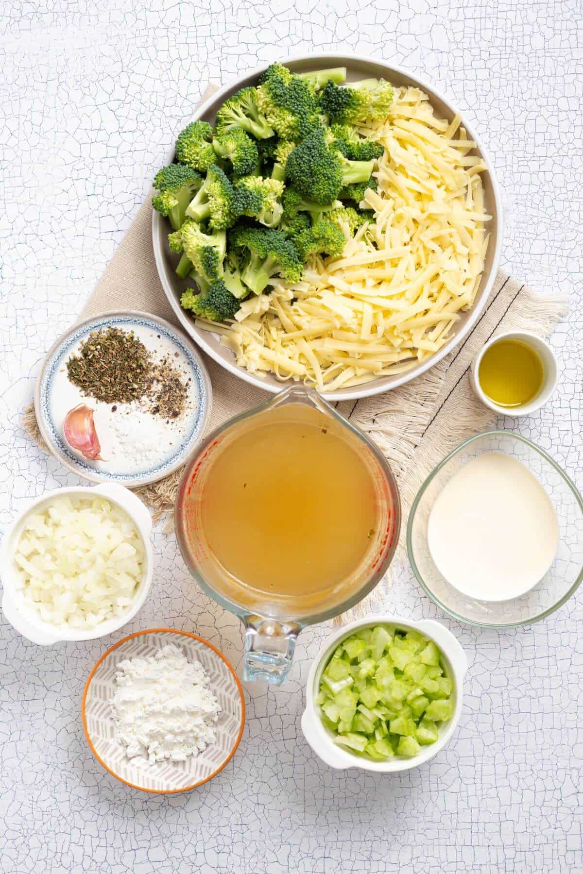 A bowl of broccoli, cheese, and other ingredients on a table.