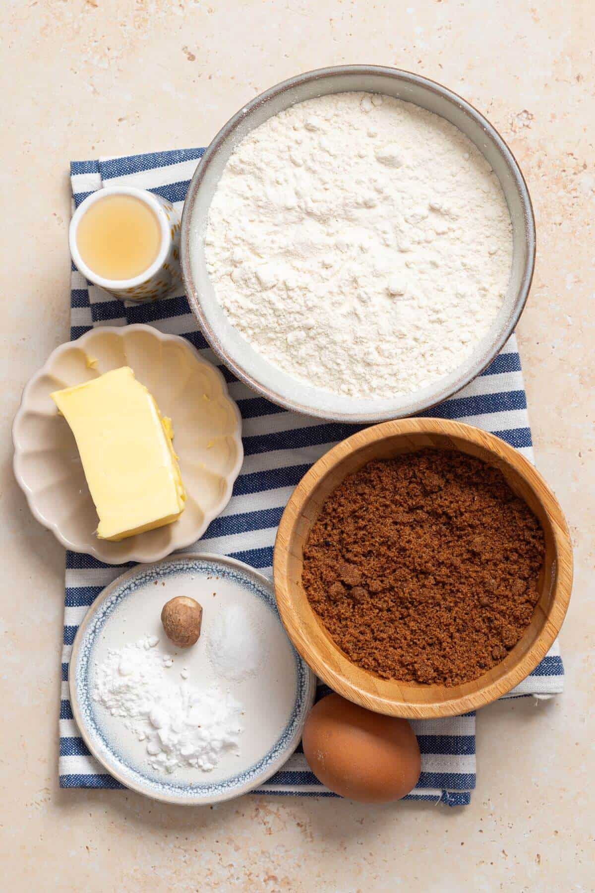 A bowl of flour, eggs, brown sugar and other ingredients on a table.
