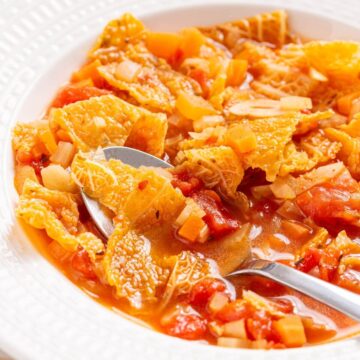 A bowl of cabbage soup with a spoon in it.
