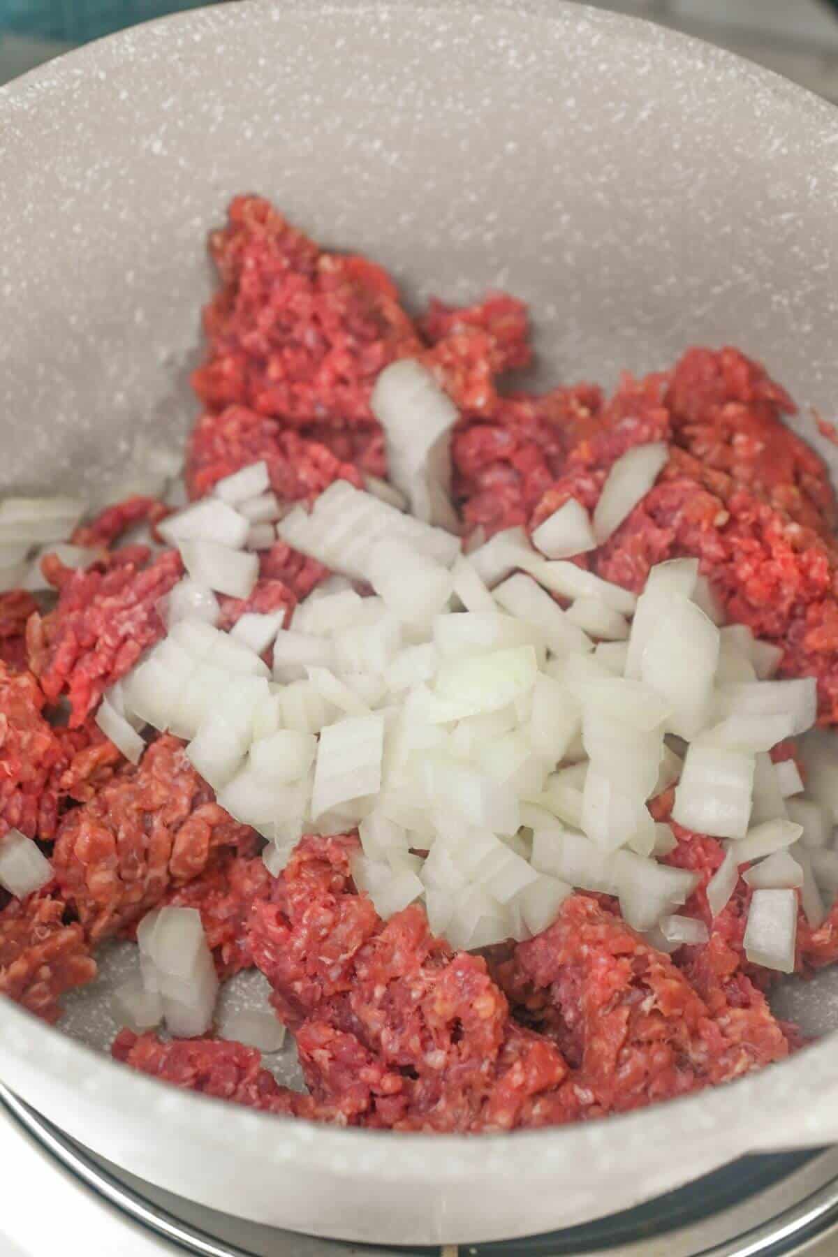 A skillet with ground beef and onions.