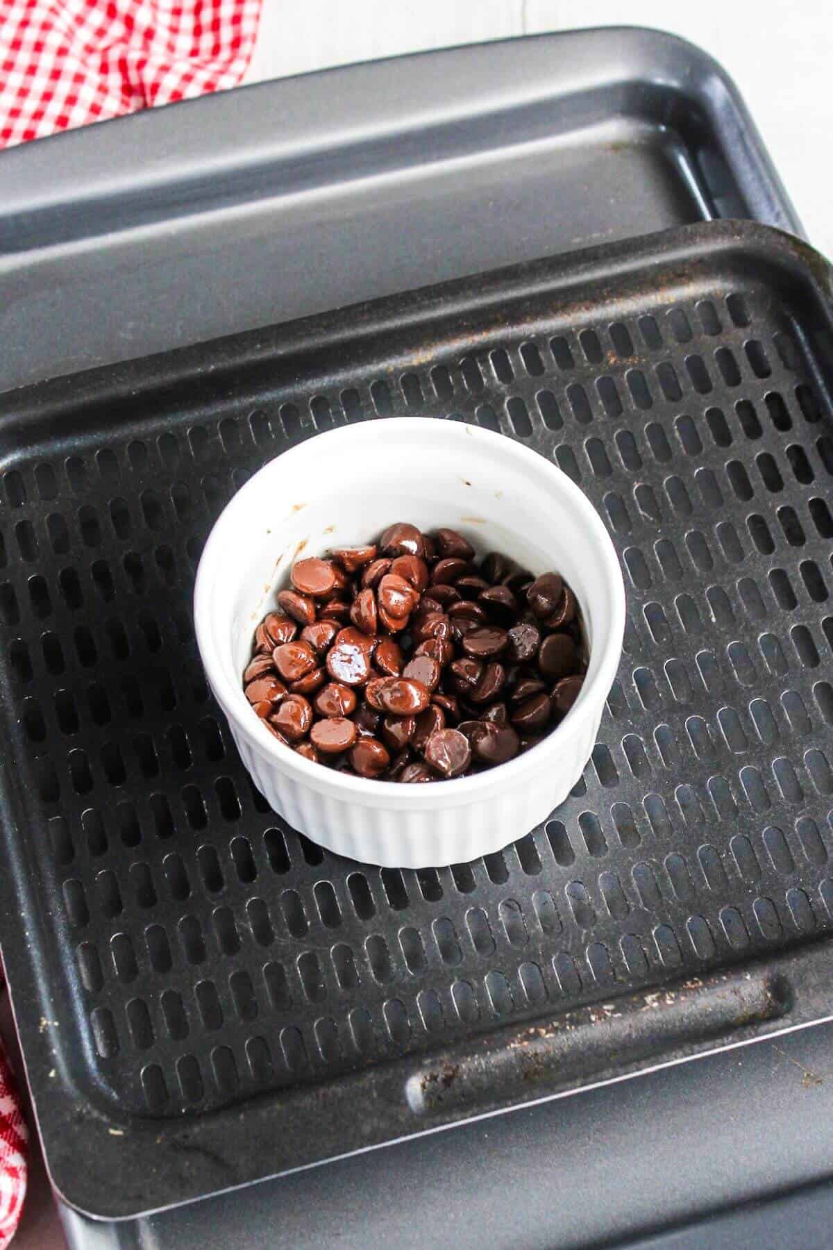 Chocolate chips in a bowl on an air fryer tray.