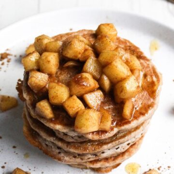 Stack of pancakes topped with cinnamon-spiced apple chunks.