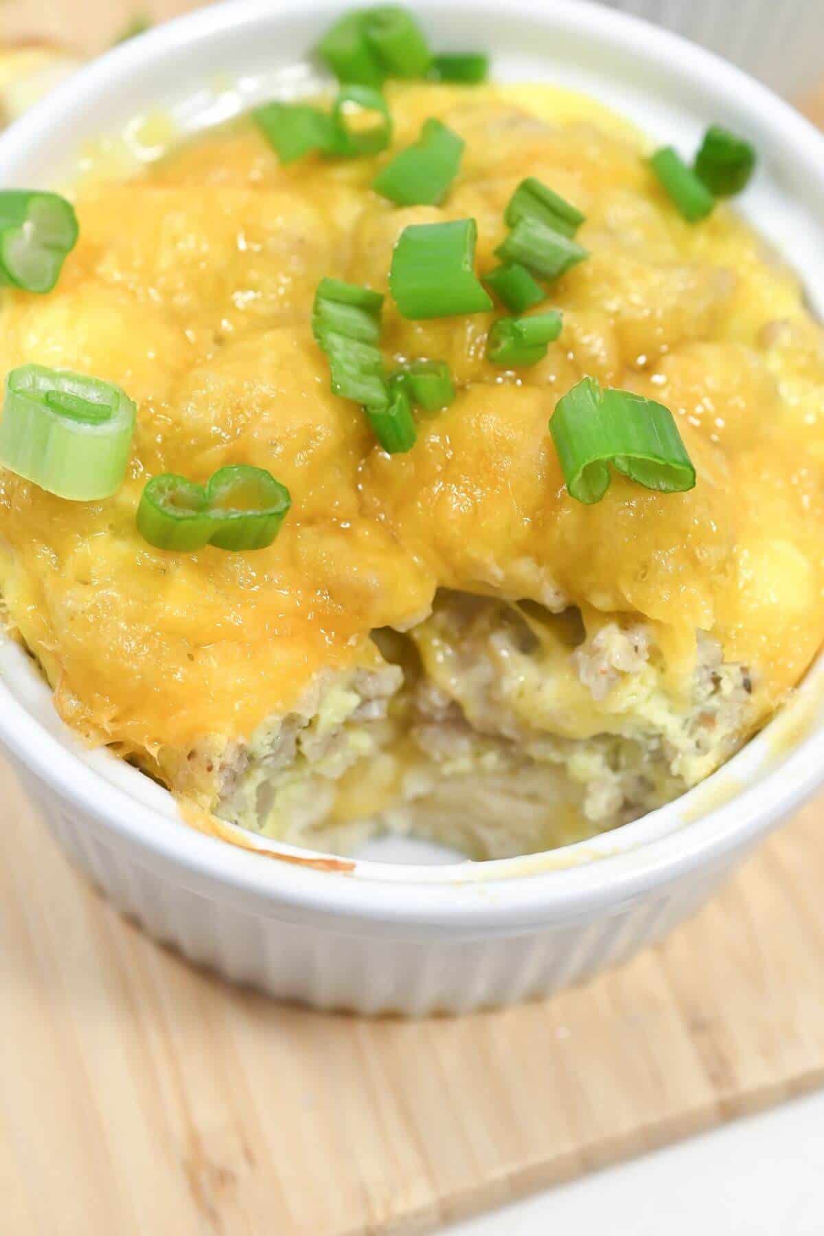 Baked breakfast casserole topped with melted cheese and garnished with green onions.