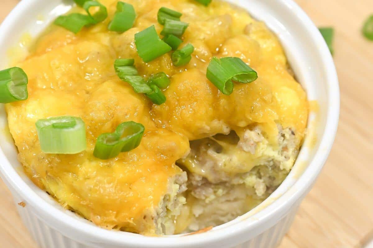 Cheesy breakfast casserole topped with green onions in a white dish.