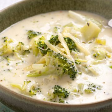 A bowl of creamy broccoli soup with chunks of broccoli, served with a spoon.