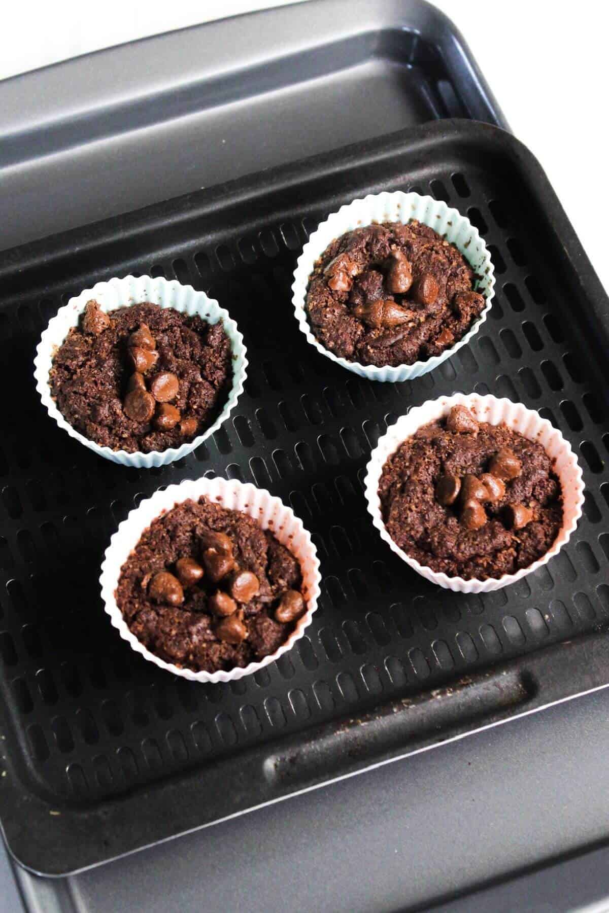 Four brownie bites in colorful paper cups on a baking tray.