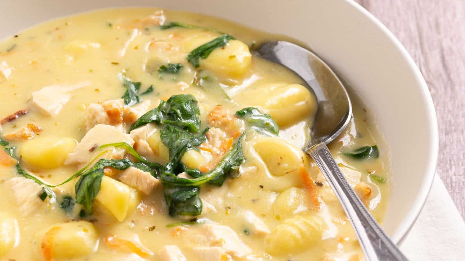 Bowl of creamy chicken and vegetable soup with spinach and gnocchi.
