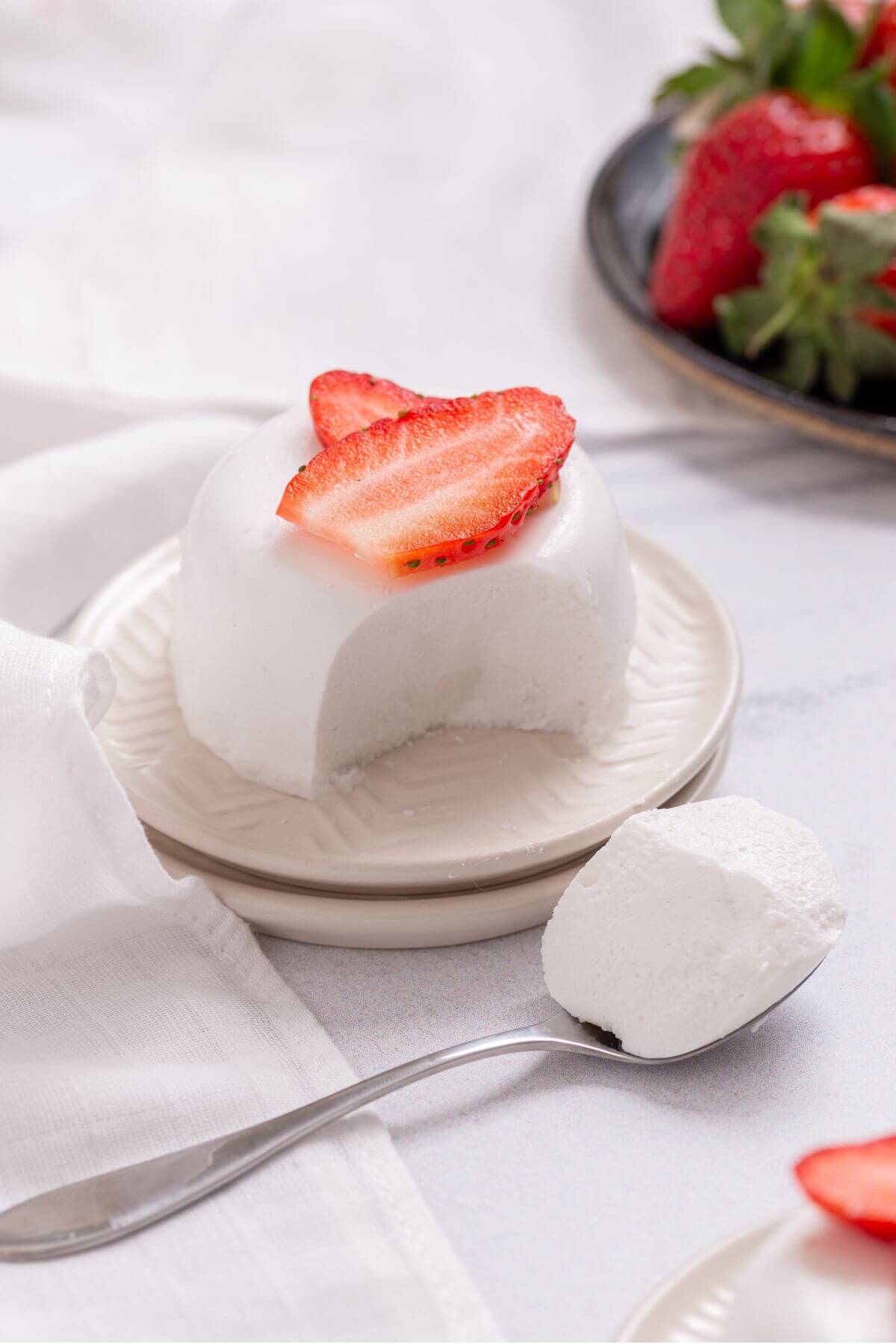 A coconut panna cotta with strawberries on a plate.