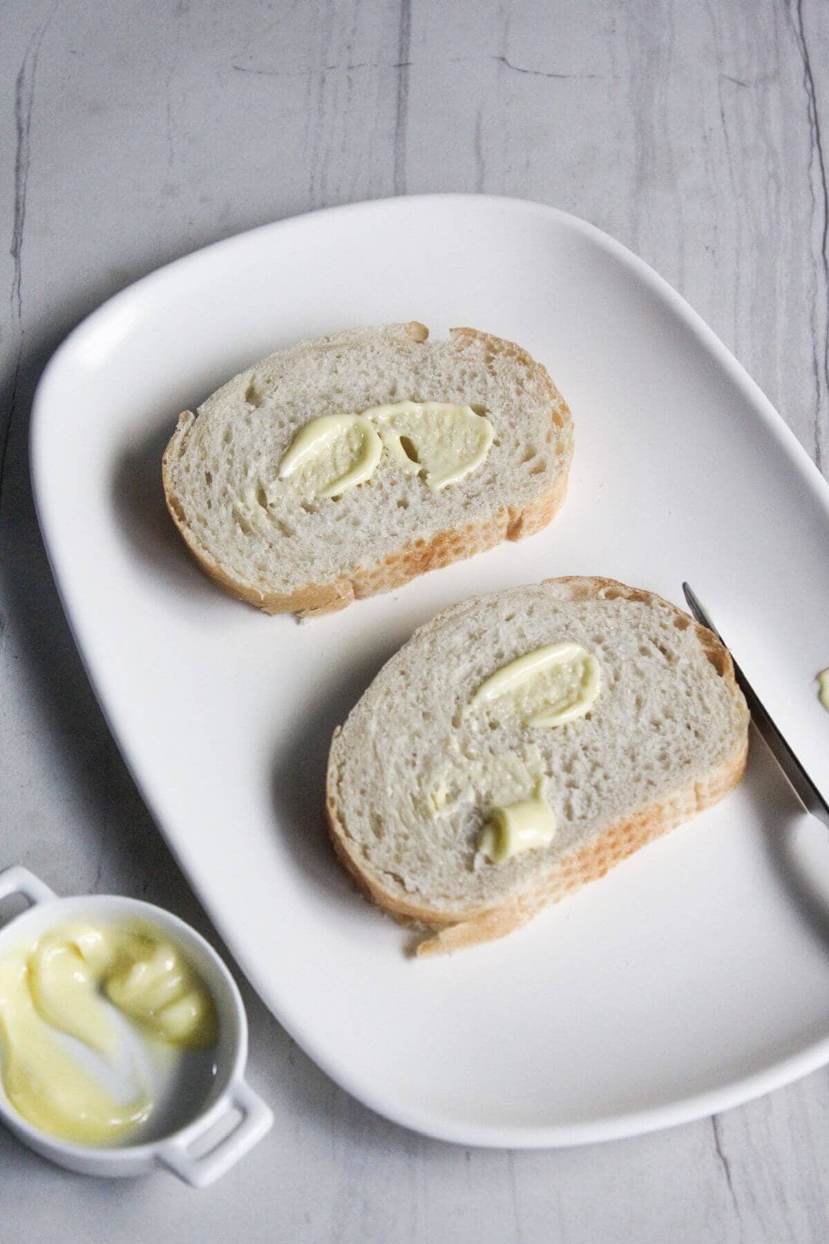 Two slices of bread with a dollop of mayonnaise on a white plate.