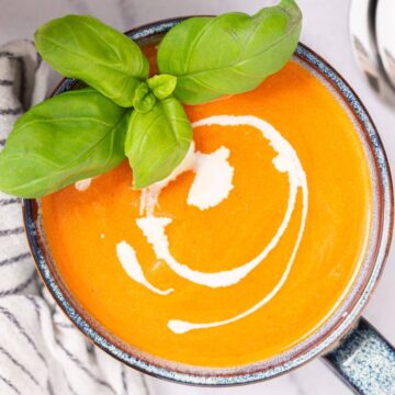 A bowl of creamy tomato soup garnished with fresh basil.