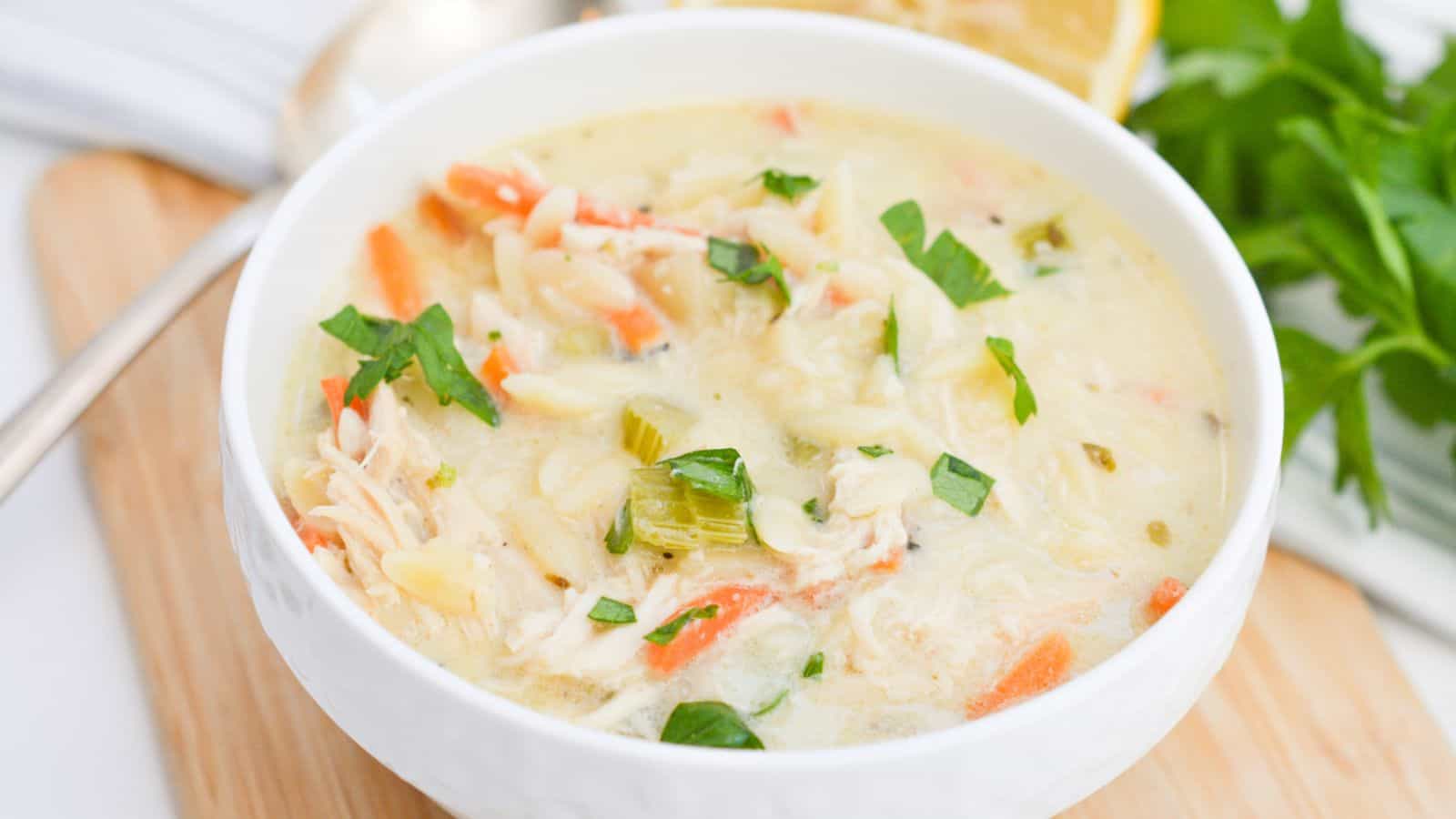 Lemon chicken soup in a white bowl with lemon slices.