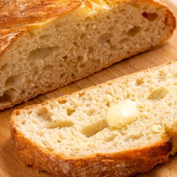 Loaf of bread sliced open with a pat of butter on one slice.