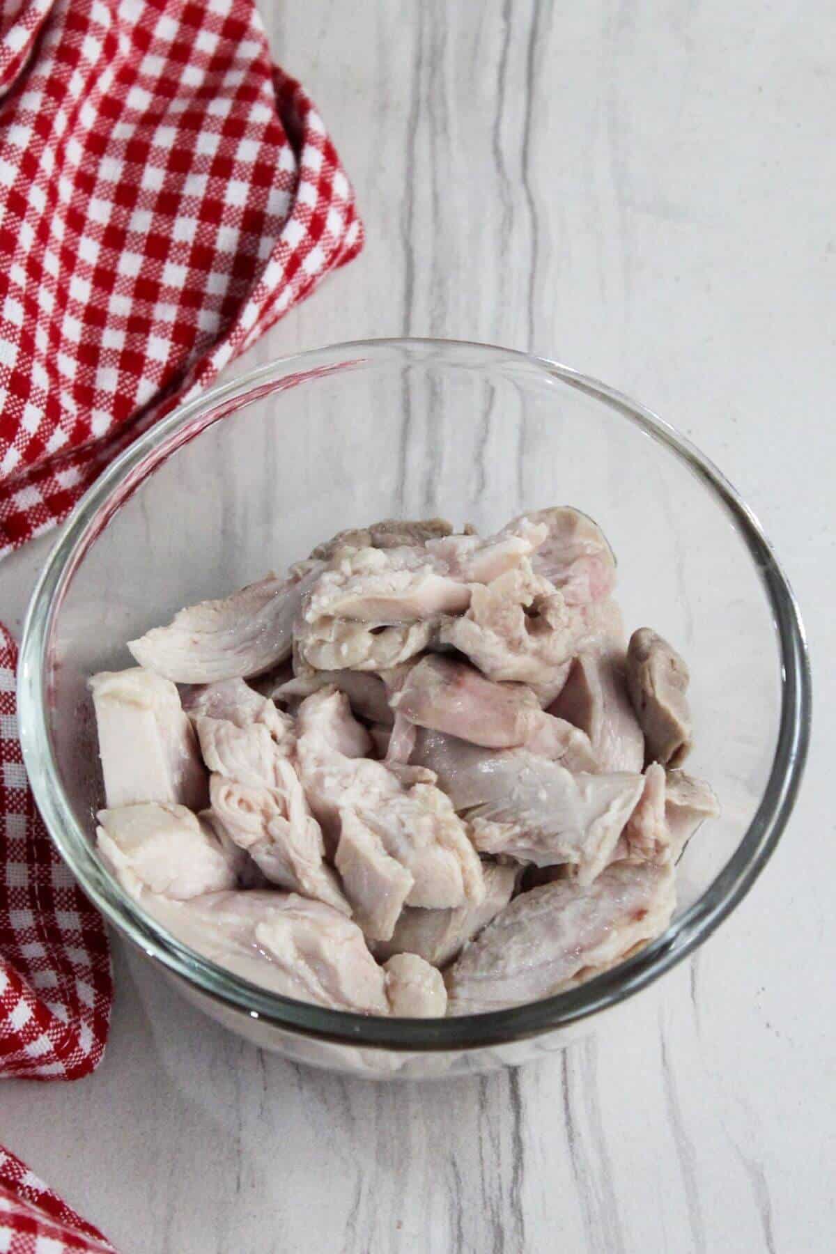 Sliced chicken thighs in a glass bowl.