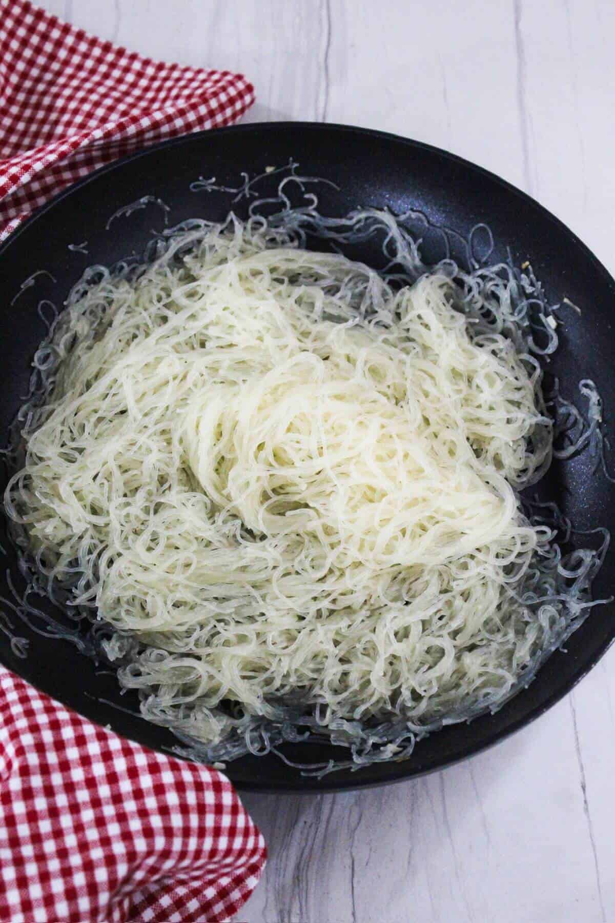 Rice noodles in a frying pan.