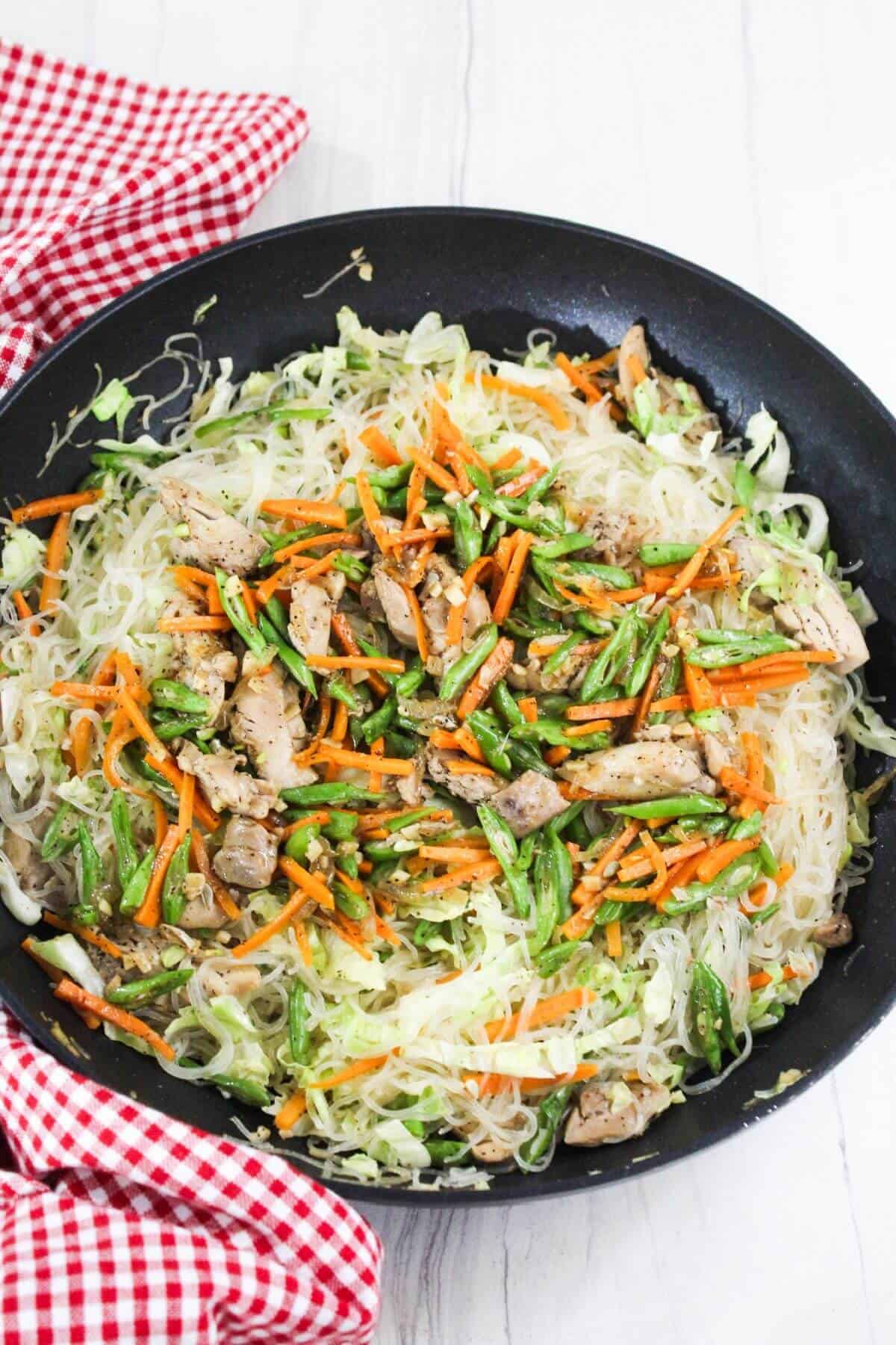 Stir fried noodles with meat and vegetables in a frying pan.