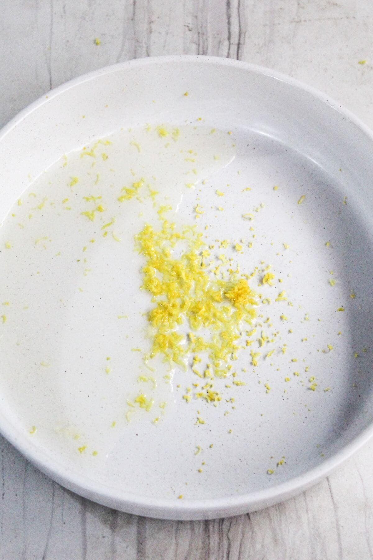 White plate with a small pile of grated lemon zest in the center.
