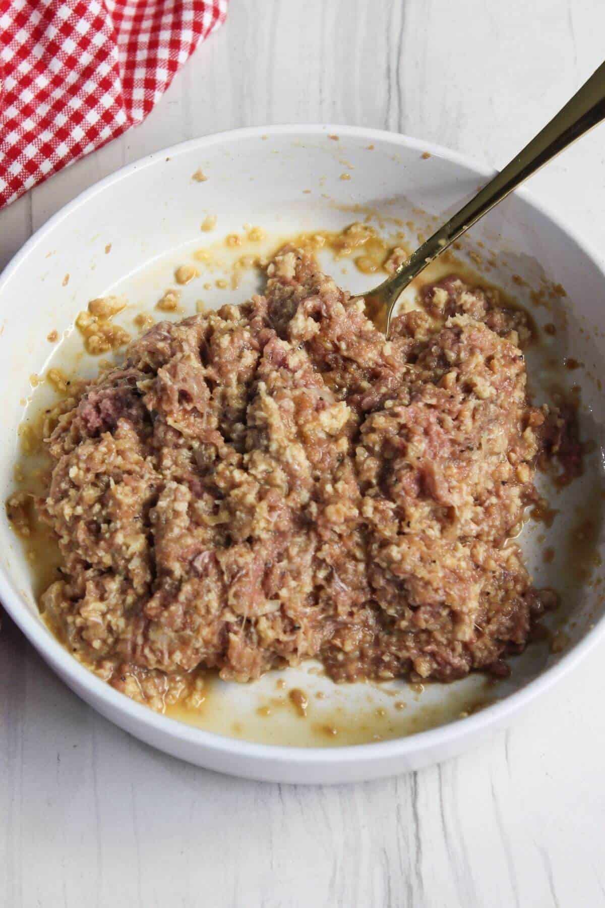 A bowl containing a mixture of ground meat with a fork sticking out of it.
