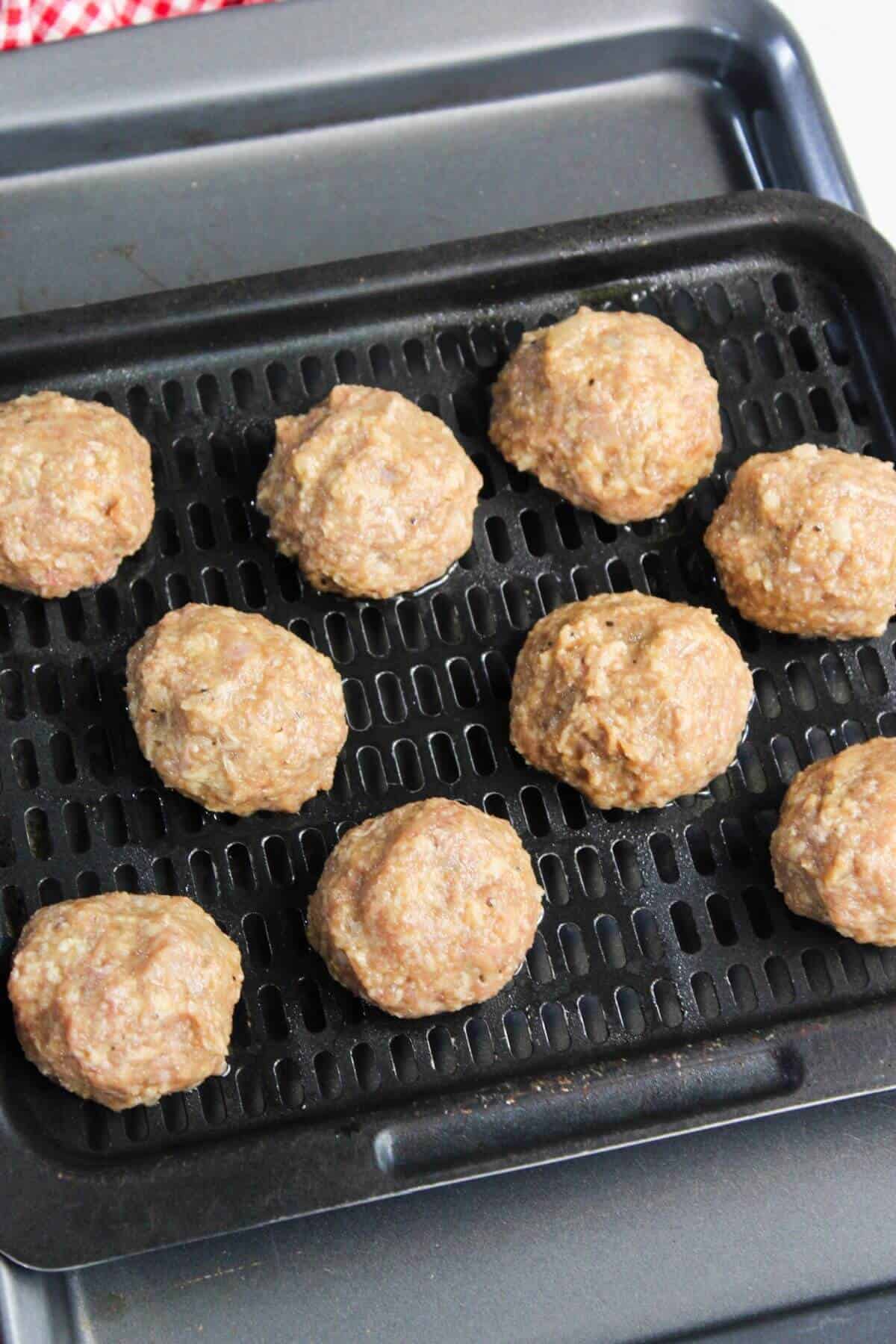 Nine raw meatballs placed on an air fryer tray pan ready for cooking.