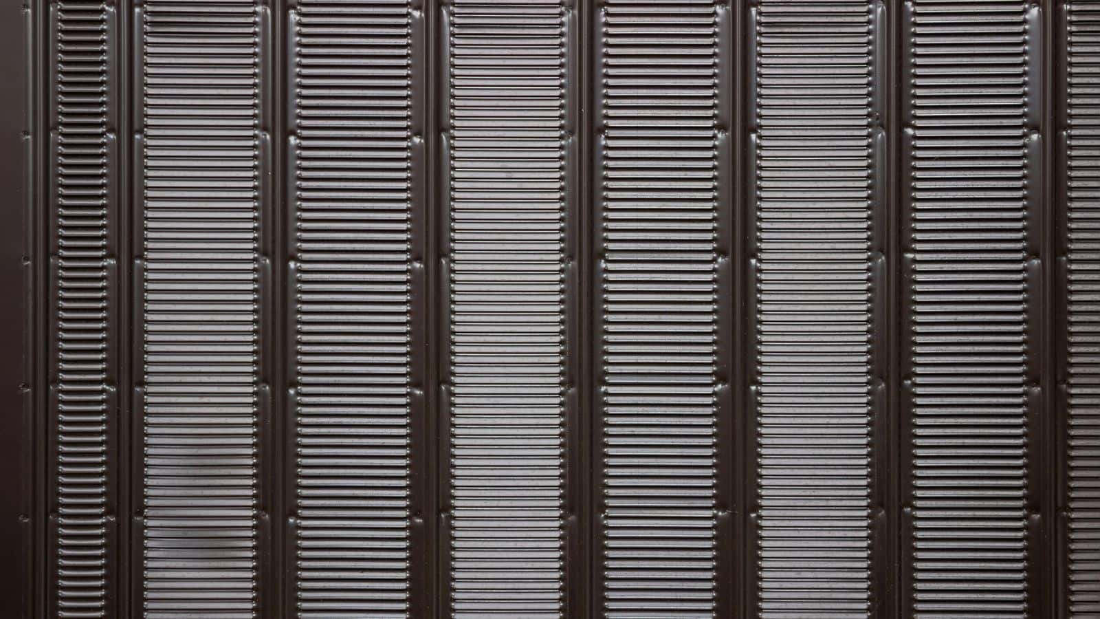 A close-up of a metallic vent cover with vertical slats and horizontal ridges creating a repeating pattern.