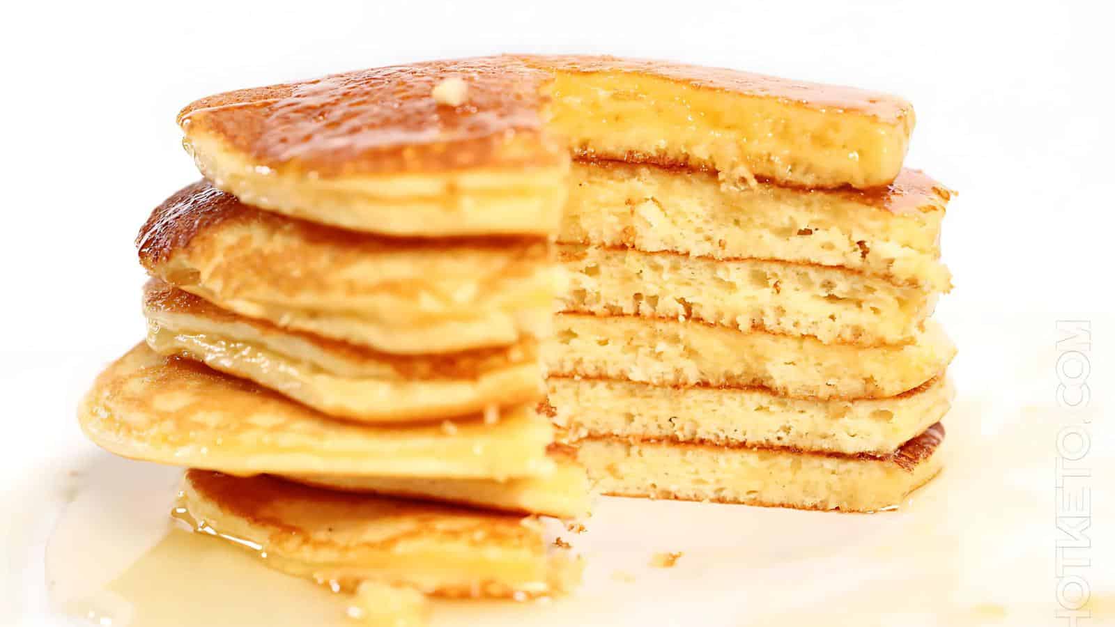 A stack of fluffy pancakes with a syrup drizzle, partially cut to show the layers.