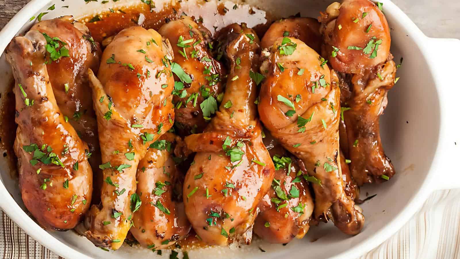 A dish of glazed chicken drumsticks garnished with fresh herbs.