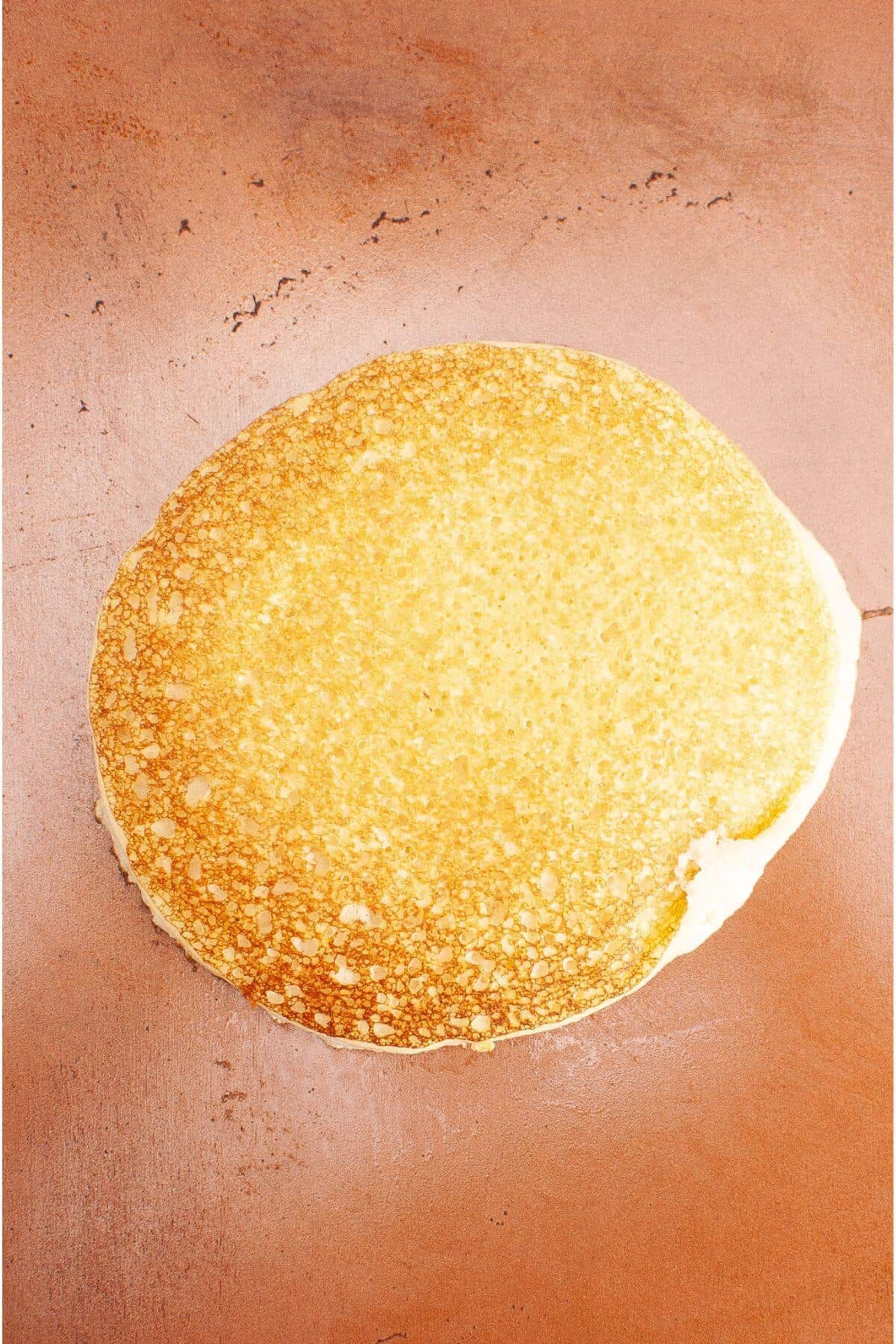 A single golden-brown pancake on a flat surface.