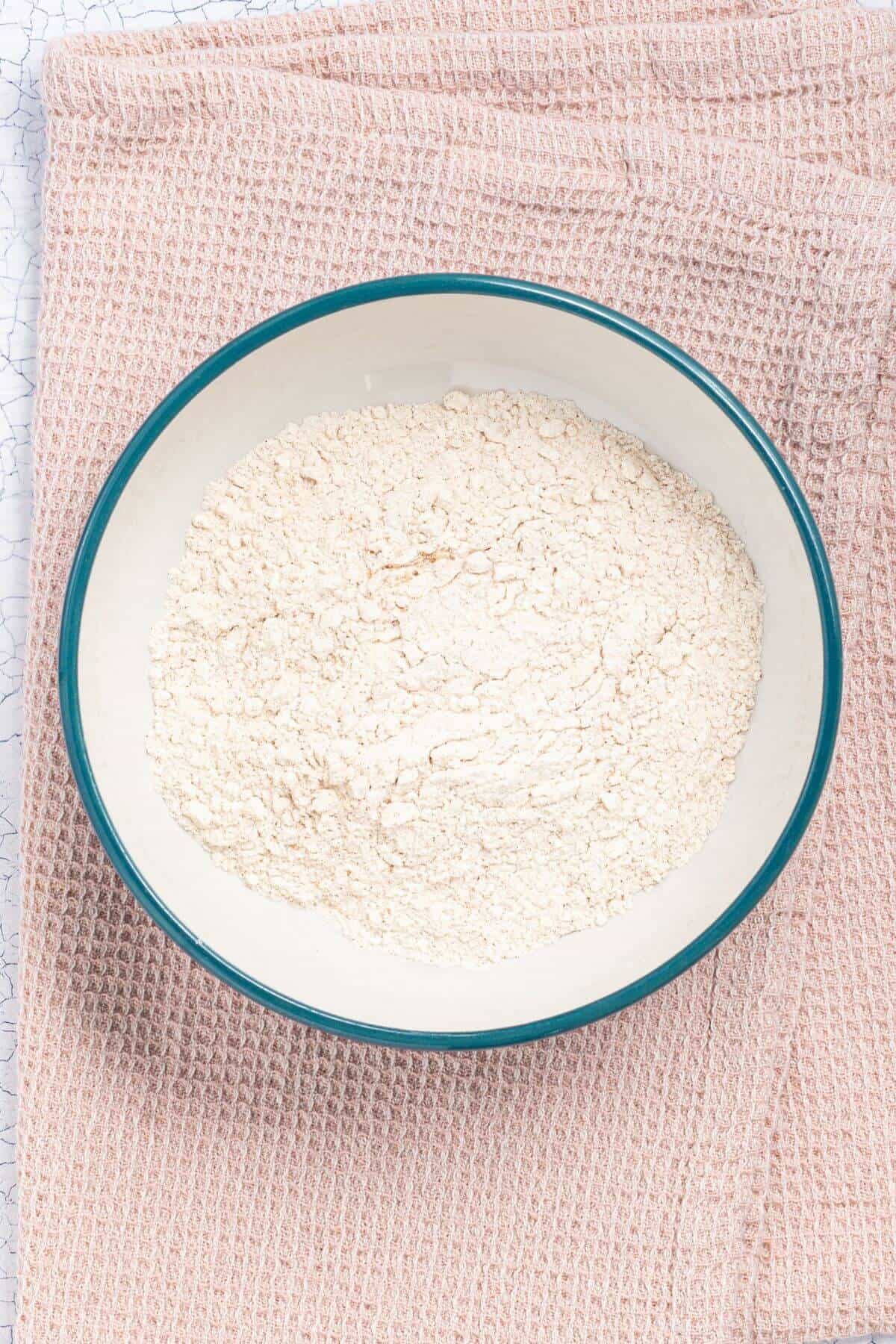 A bowl filled with flour placed on a folded pink fabric.
