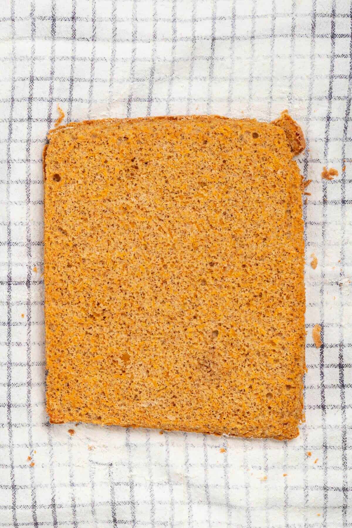 A single slice of brown bread on a white and gray checkered cloth.